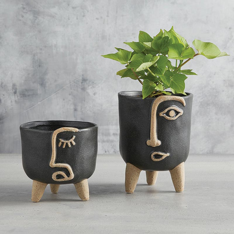 small and large face planter displayed with a plant in the large against a gray background