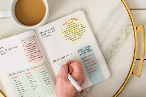 book open with hand writing in fill in the blanks in book with coffee on table