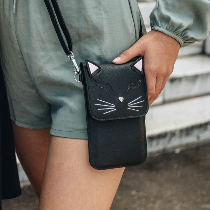 hip view of a woman modeling the black just for fun cat purse while walking outside