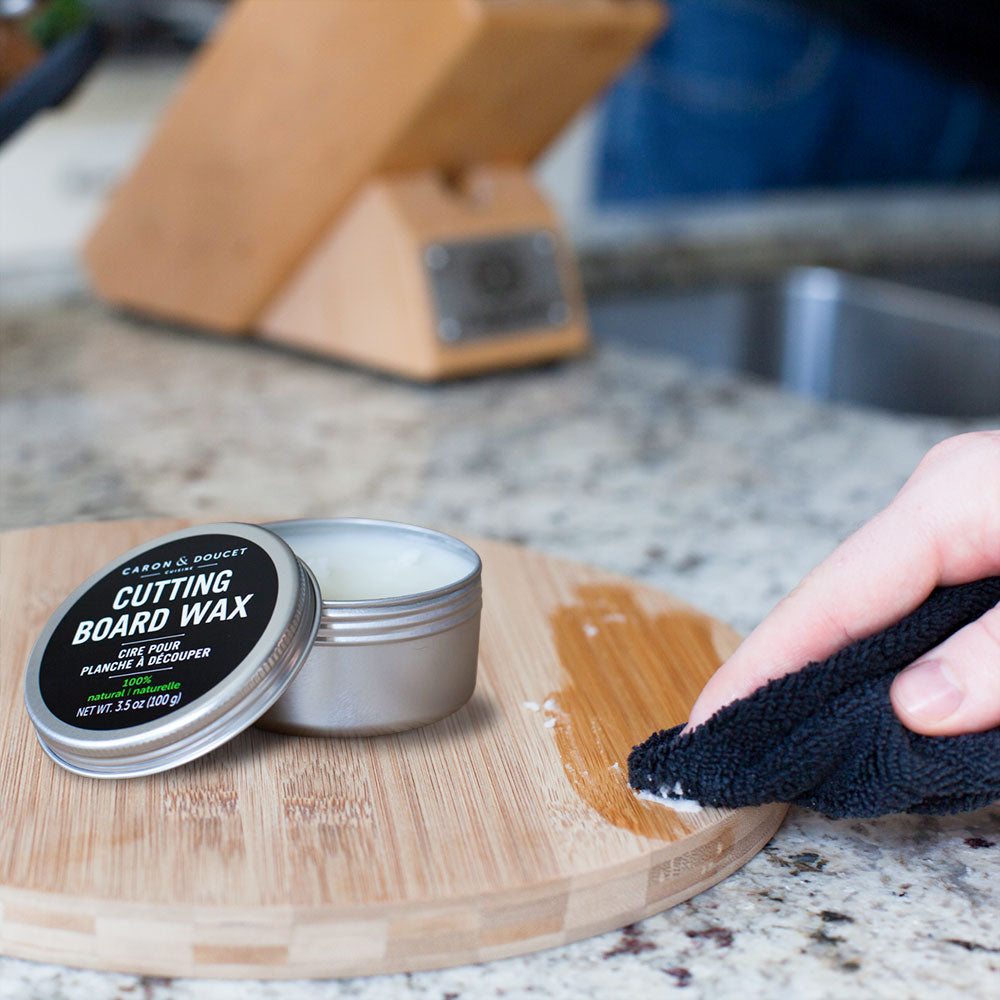 the cutting board wax being used on a cutting board in a kitchen on a granite countertop