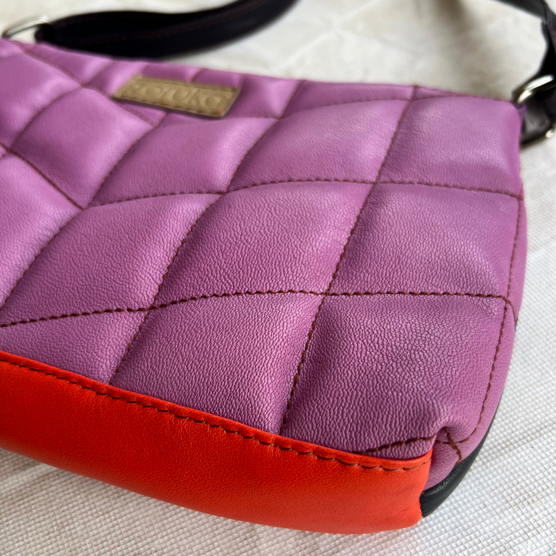 angled bottom view of purple purse with orange base.