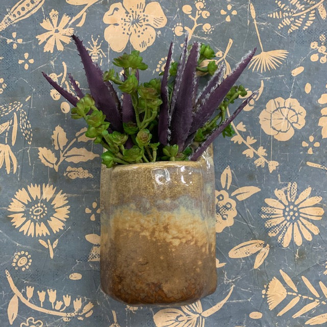 light glaze stoneware wall planter displayed with greenery against a blue and pink floral background