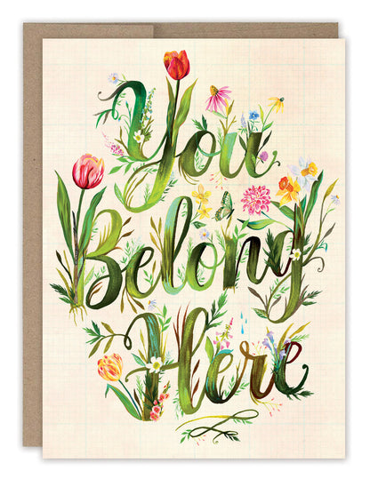 front cover of card has text out of green leaves and flowers growing out of them and a natural envelope behind it on a white background