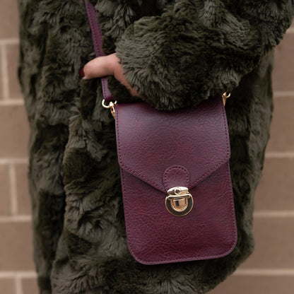 a woman modeling the little purse against her furry coast while standing in front of a brick wall