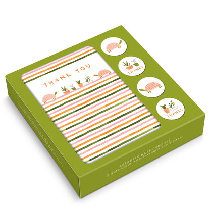 box of notecards on white background. box has olive green background with graphics of turtles and house plants, horizontal stripes in green, orange, and pink, and the words "thank you" in the top center.