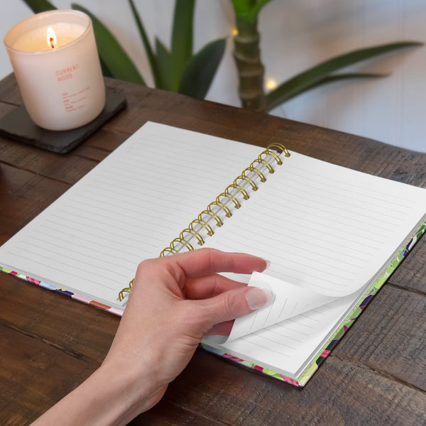 open notebook showing lined pages with hand turning a page sitting on wooden table with candle.
