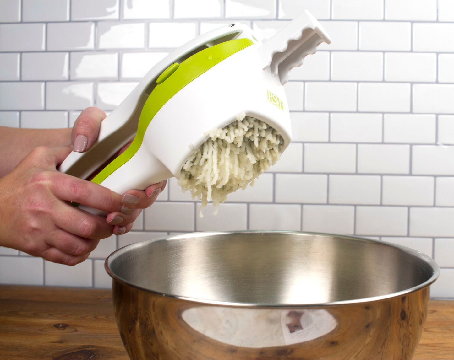 hands holding ricer over bowl.