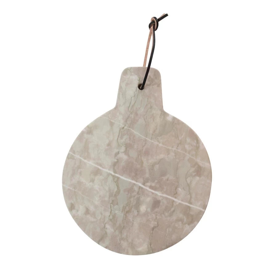 round taupe marble board with small handle and leather strap on a white background.