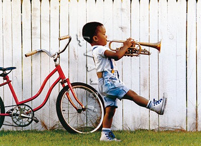 front of card is a photo of a small boy marching and playing a trumpet