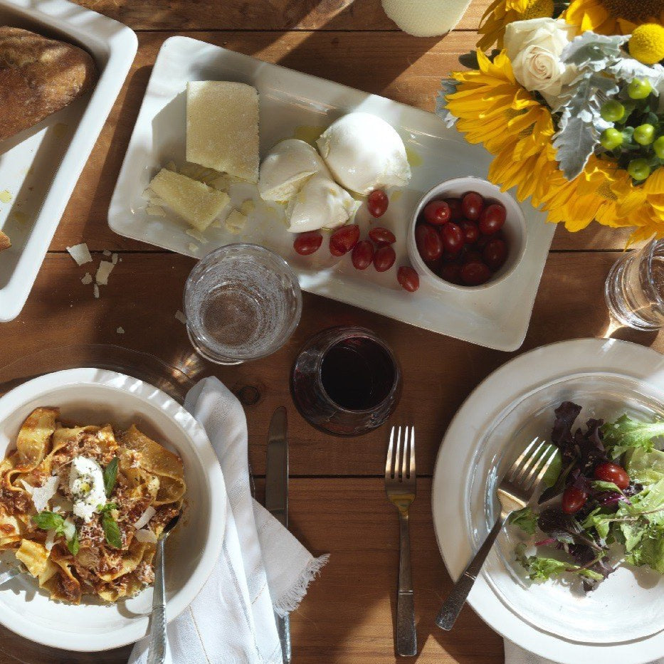 table setting with puro dinnerware, floral arrangements, glasses on a rustic wood table.