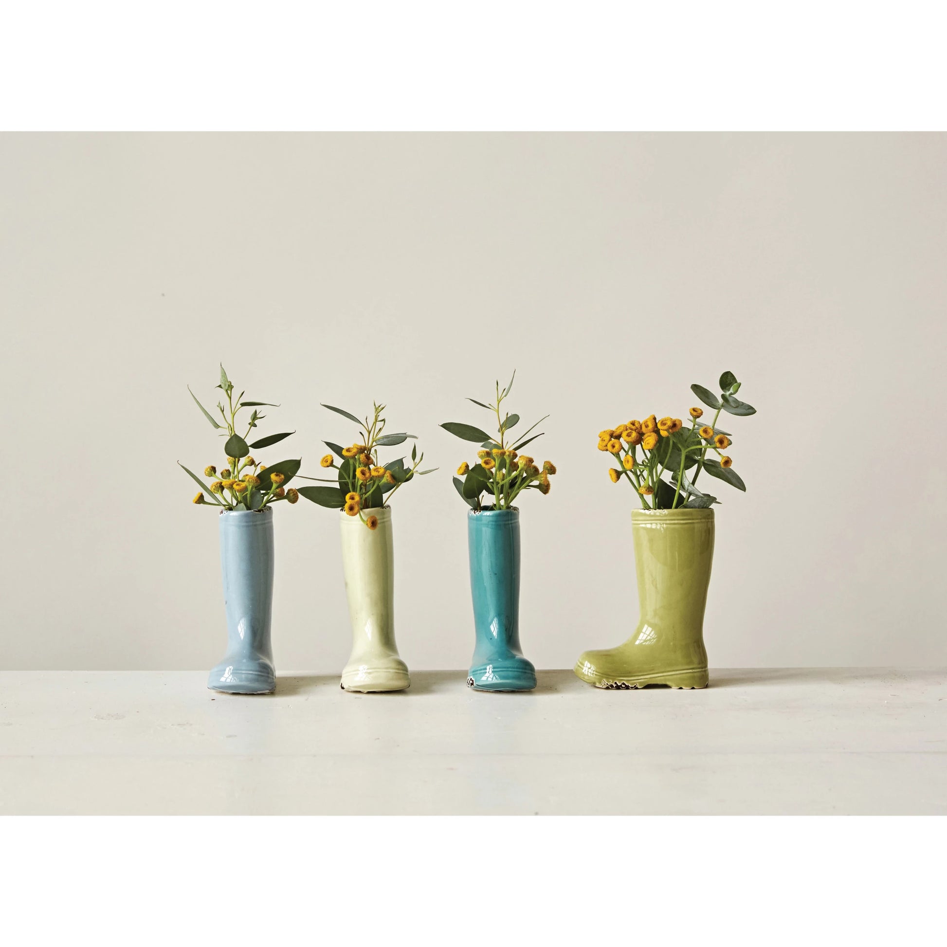 4 cilors of petite boot vase with small yellow flower sin them on a beige back ground.