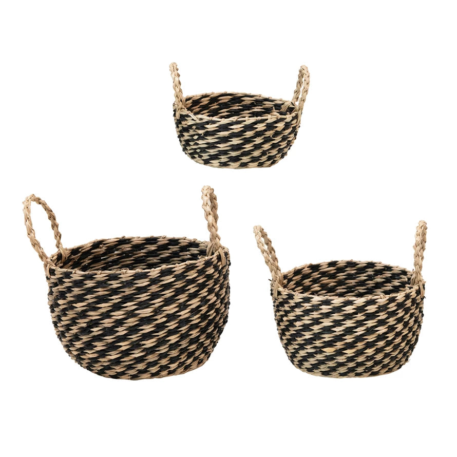 all three sizes of hand woven seagrass baskets with handles are black and natural against a white background