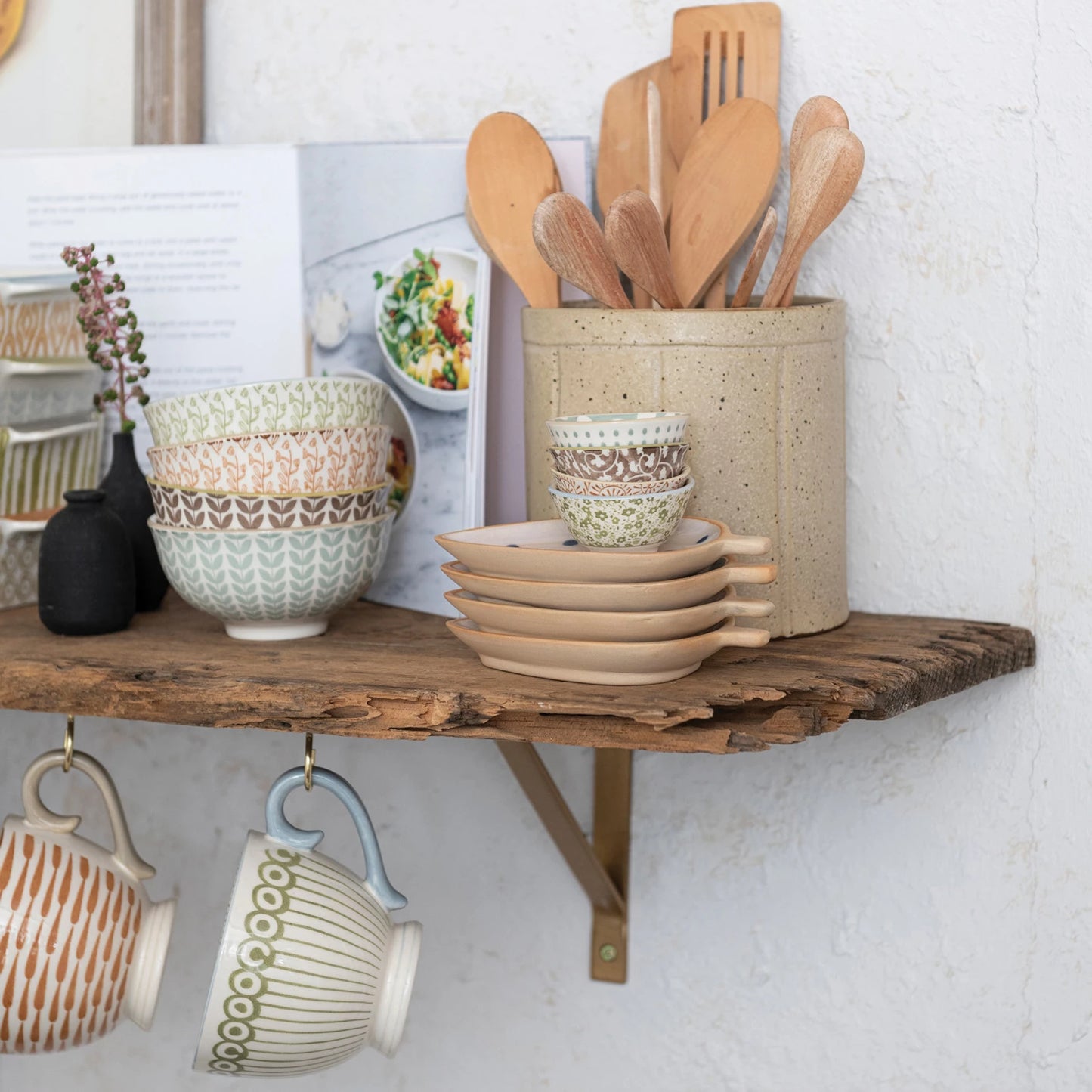 kitchen shlef with assorted bowls, mugs, and utensils on it.