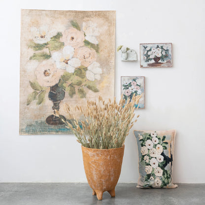 decorator paper with flowers in a vase displayed hanging on a wall with smaller floral prints and a vase full of dried grass sitting on a table beneath it