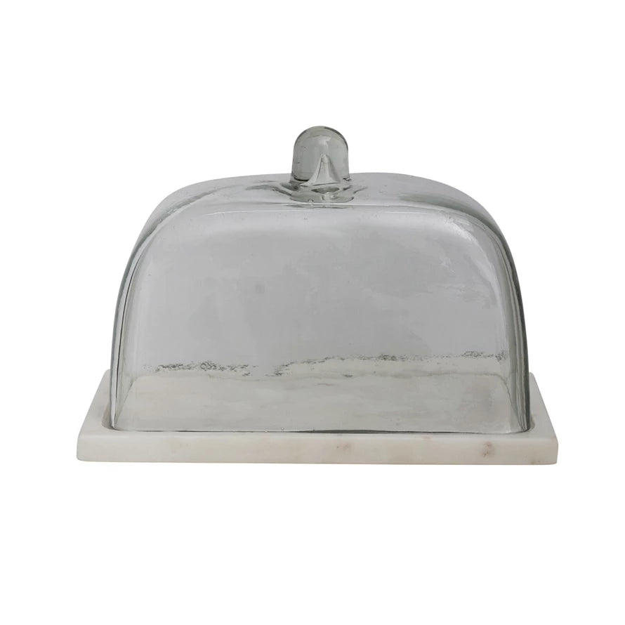 rectangle clear glass cloche sitting on a white marble base against a white background