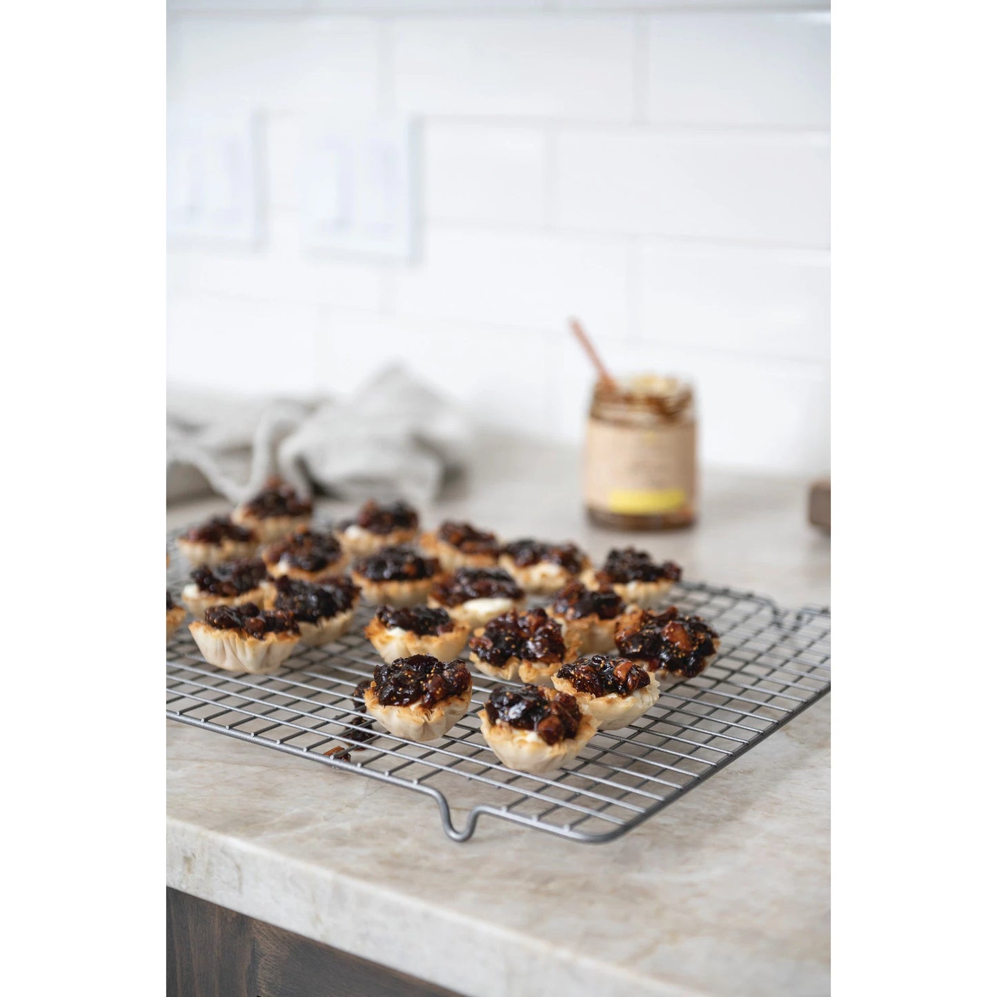 pastries cooling on a rack on the counter that have been topped off with lemon fig marmalade and the jar sitting next to it