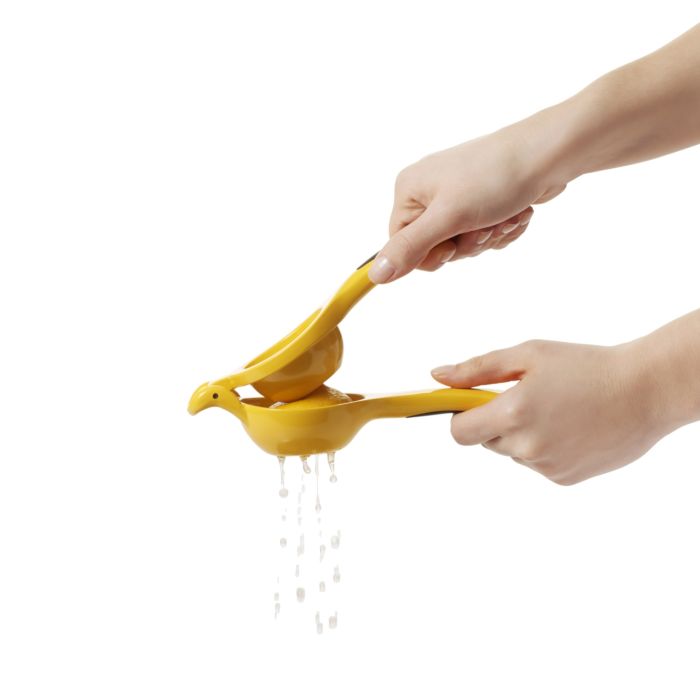 hand squeezing lemon in squeezer with juice dripping out of it.