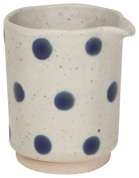 off-white speckled creamer with bright blue dots.