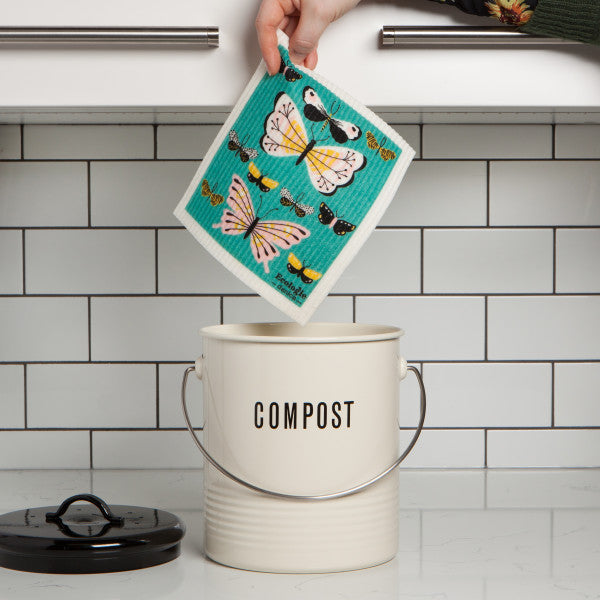 hand holding swedish dish cloth above compost pail.