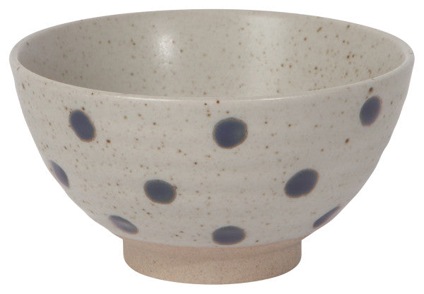 off-white speckled bowl with blue dots on a white background.