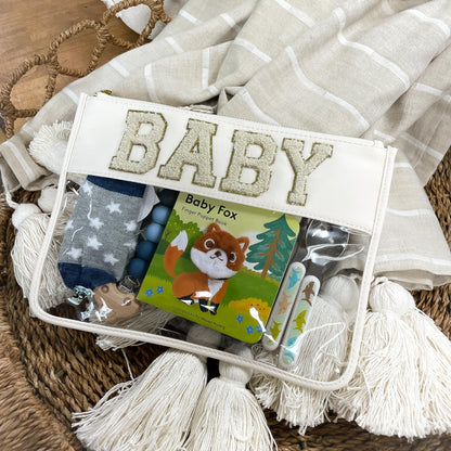 clear nylon bag with cream trim and chenille patches that spell "baby" filled with baby items.