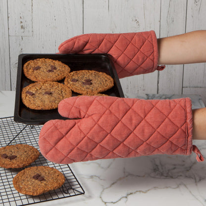 hands wearing mitts holding pan of cookies.