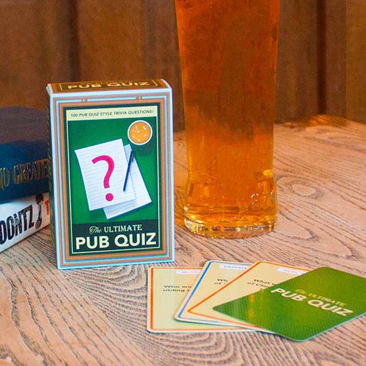the pub quiz trivia displayed on a table next to a drink