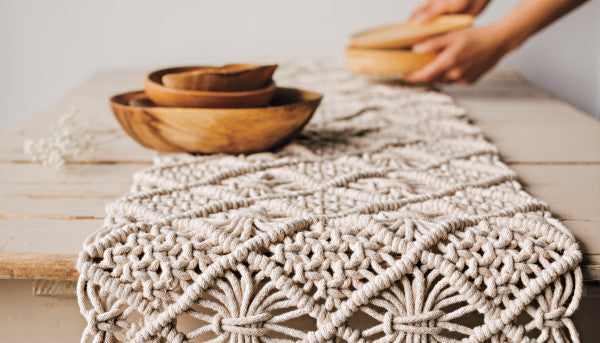 macrame table runner on table with wooden bowls.