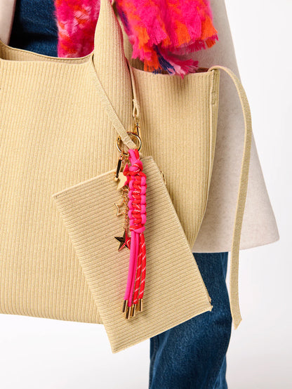 close-up of pink Starlet Bag Charm hung on a beige tote