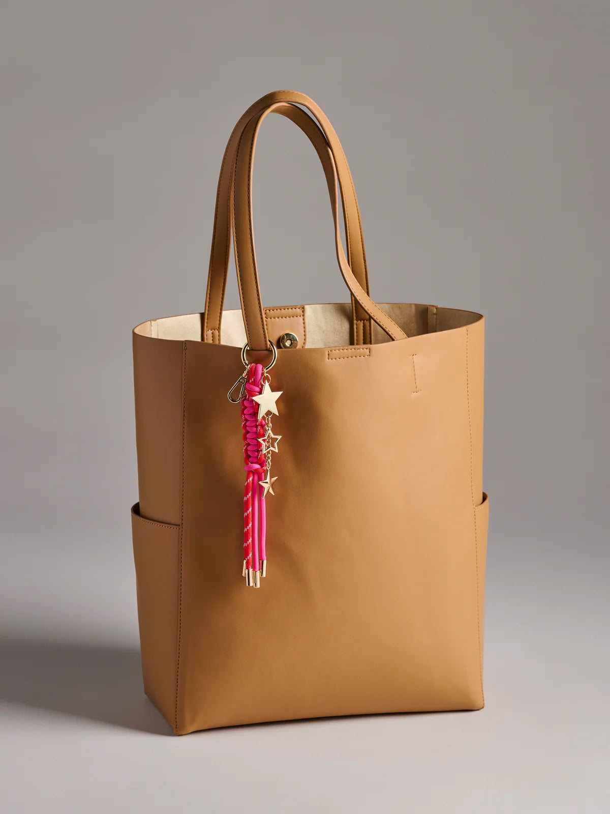 pink Starlet Bag Charm hung on a brown tote bag