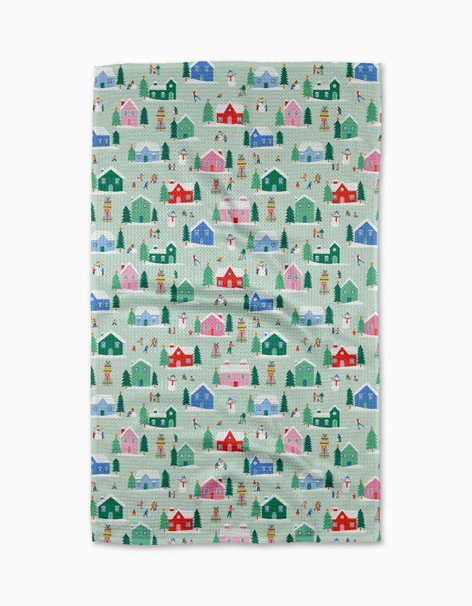 winter magic tea towel featuring a light green background overed in colorful houses