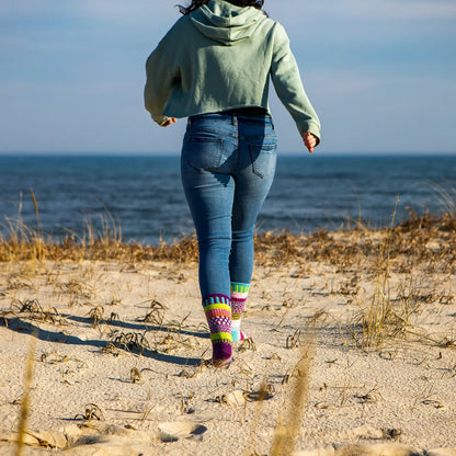 person wearing jean, sweatshirt, and Dahlia Crew Socks walking on sand to the beach