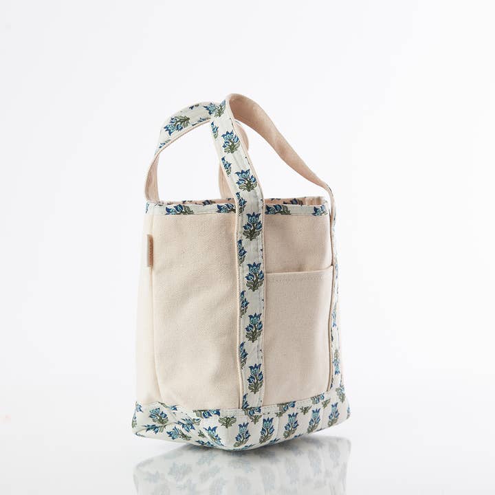 angled view of off white tote with aqua floral printed handles and trim