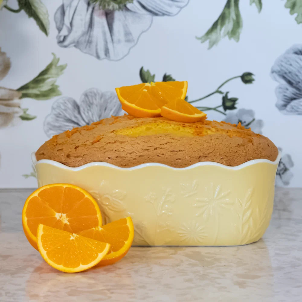 orange cake baked in a ceramic loaf an arranged on a table with orange wedges