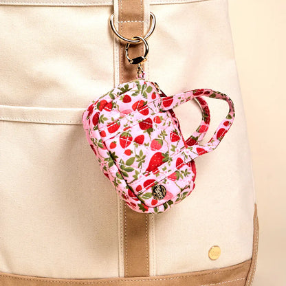 tiny duffle bag with strawberry pattern clipped to a beige and cream tote bag