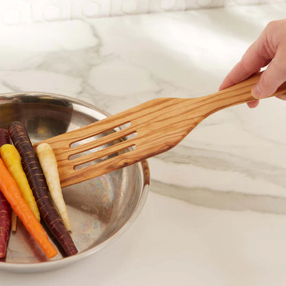 hand using Olive Wood Slotted Spurtle to move veggies in a pan