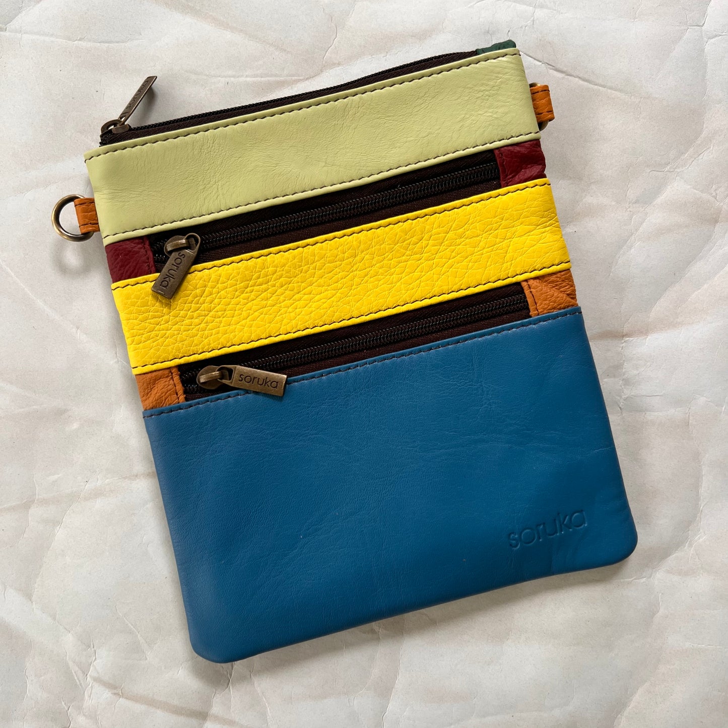 flat rectangular maya bag with top zipper and 2 zipper pockets color blocked in blue, yellow, and light green.