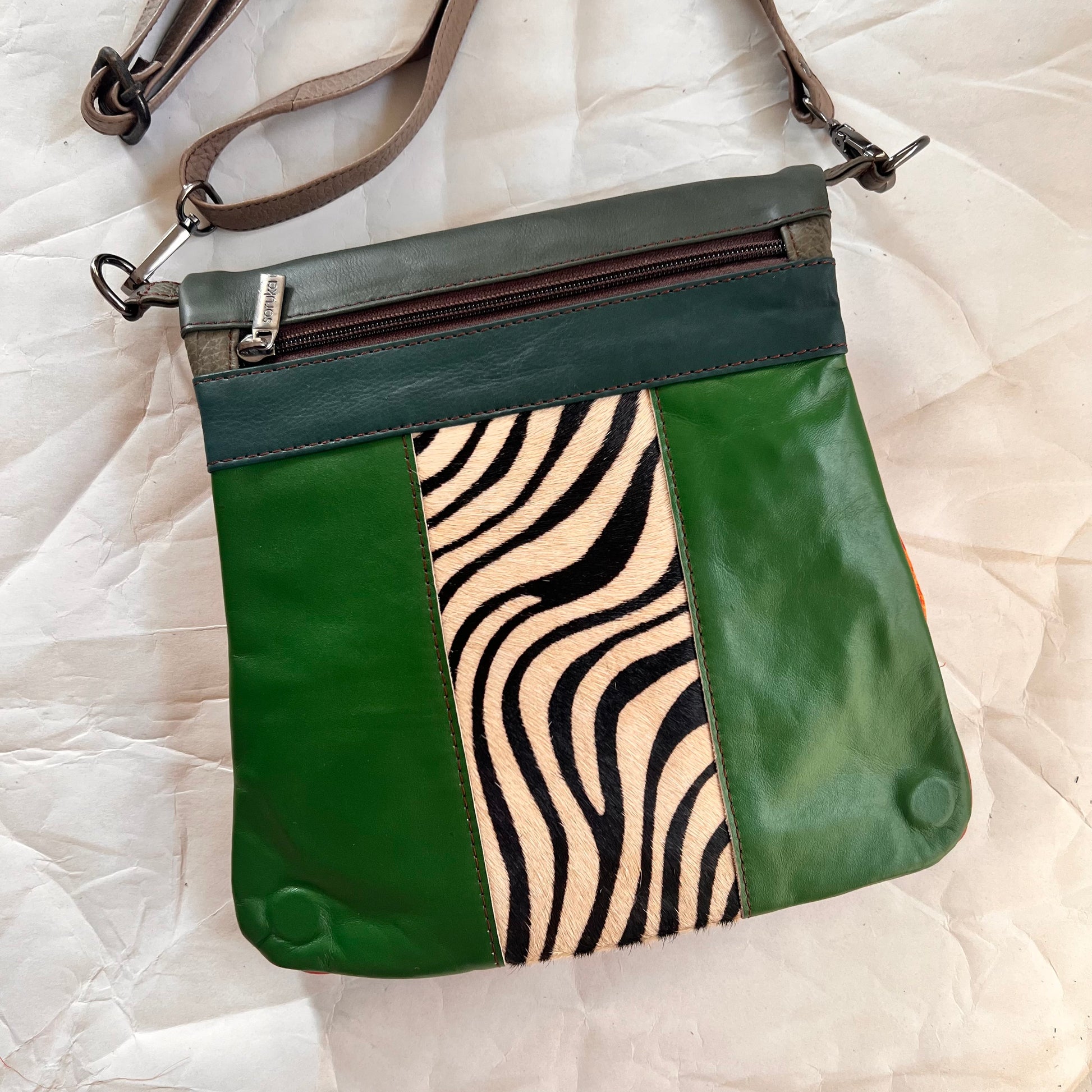 green greta bag with black and white animal print stripe down the center with teal stripe and zipper across the top.