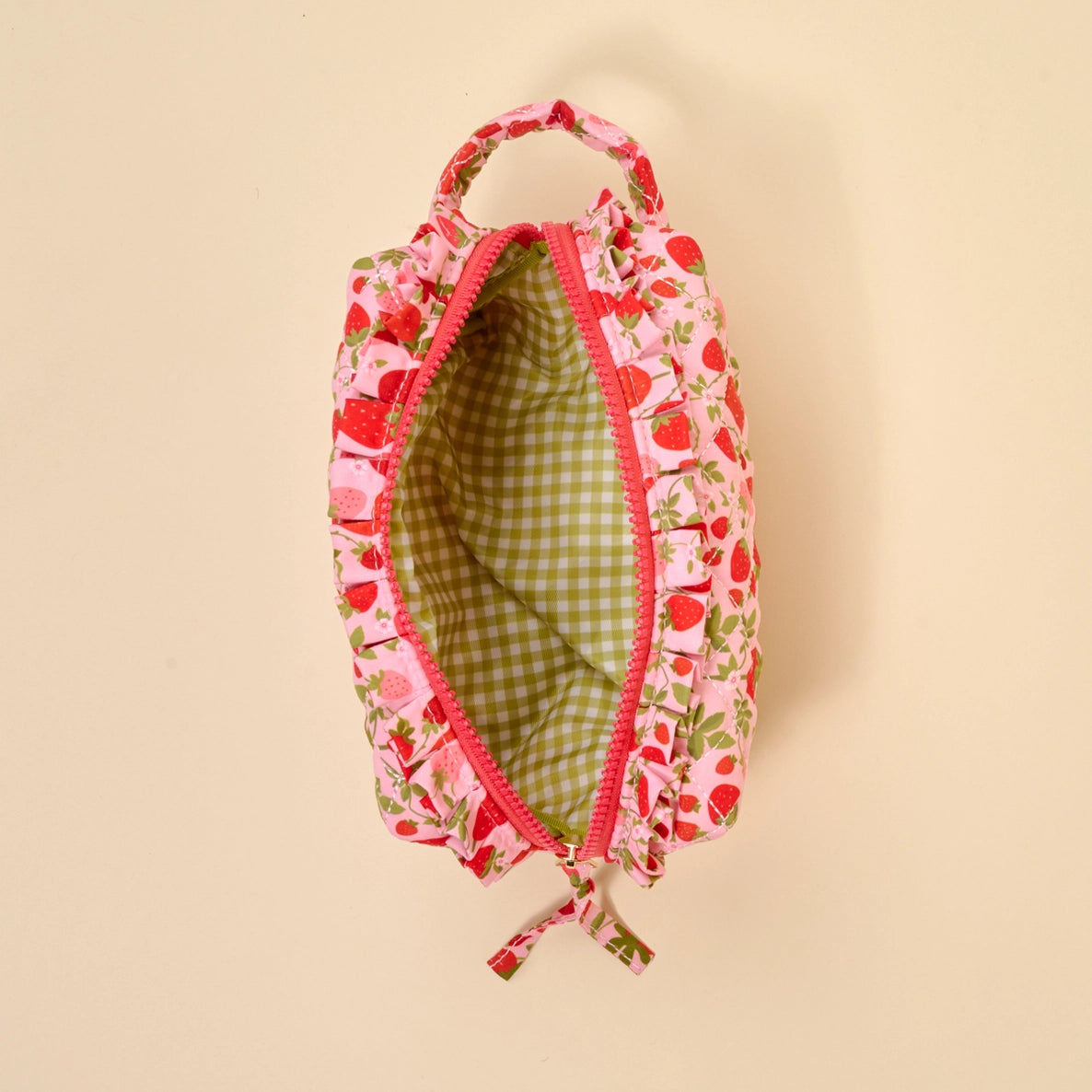 strawberry pouch with green gingham interior on a beige background
