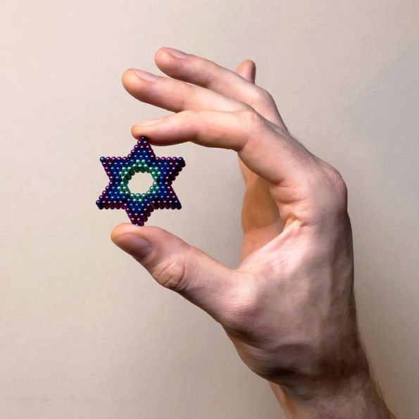 hand holding star shape made of purple, green, and blue magnetic balls