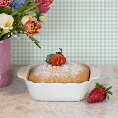 ceramic square baking dish with baked dessert in it on a surface with a green background