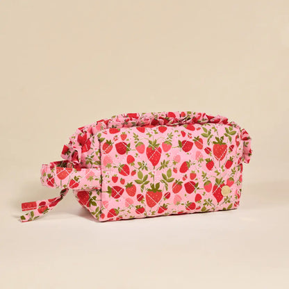 Pink cosmetic bag with strawberry pattern on a beige background