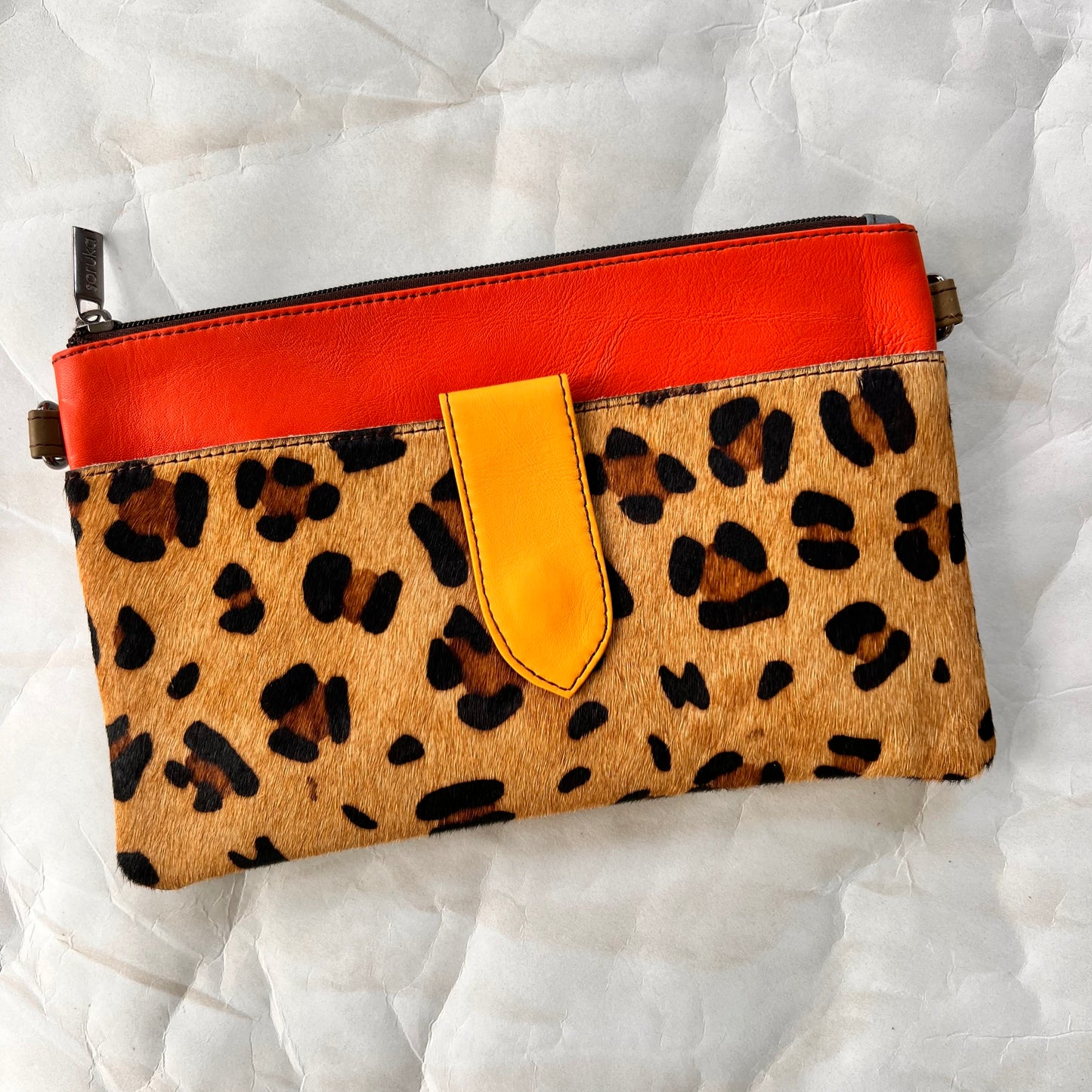 orange rectangular bag with cheetah print hair-on-hide pocket, and yellow tab.