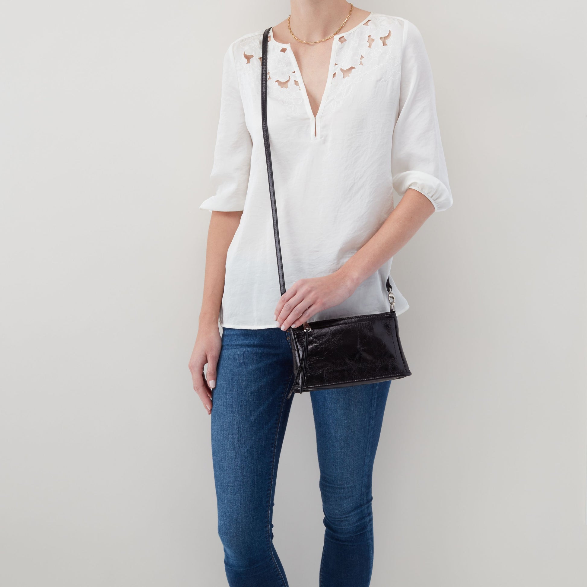 person wearing jeans a nd a white top with black cadence warn as a crossbody.