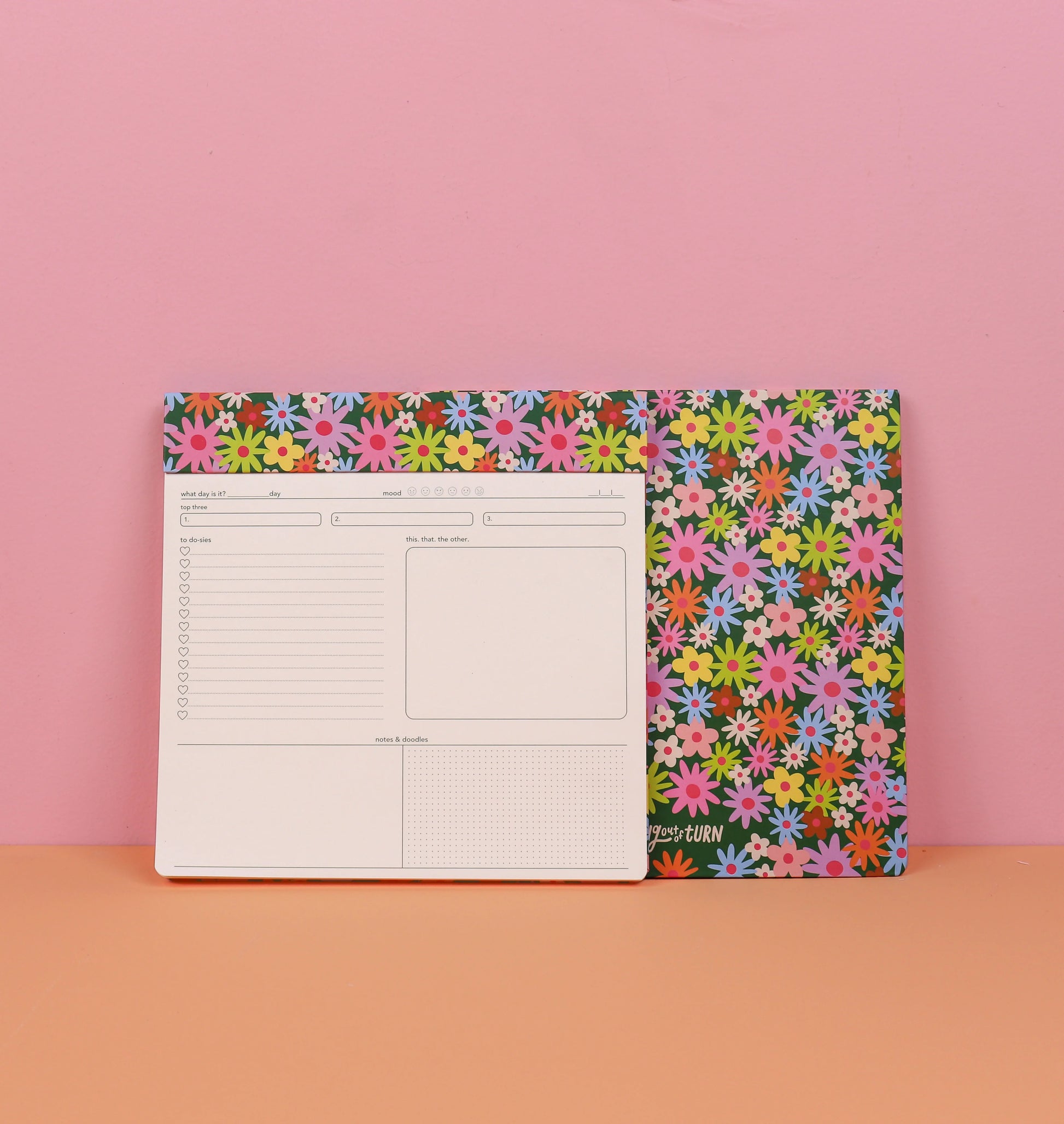 Floral-patterned note pad on a pink and orange background