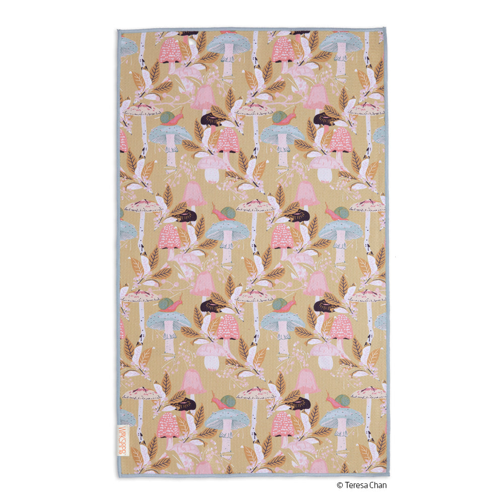 beige towel with mushroom and foliage design laying on a white background
