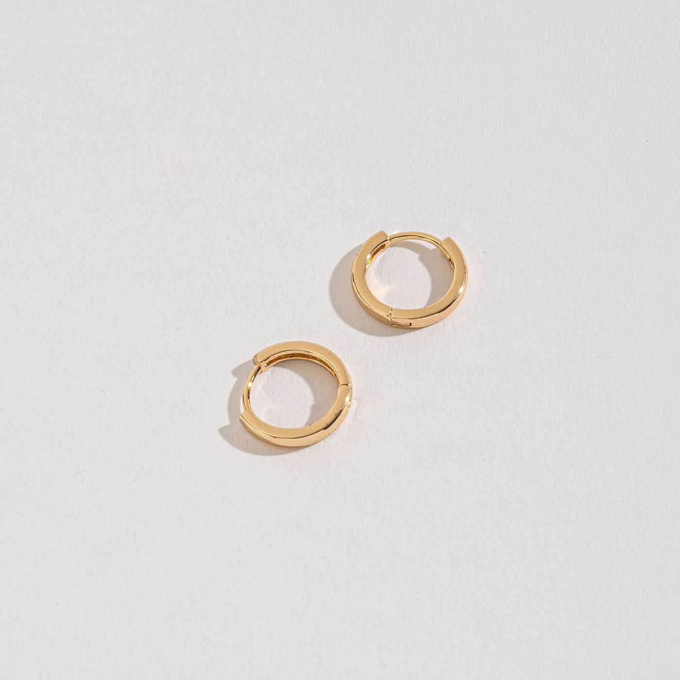 gold medium huggie hoops on a white background.