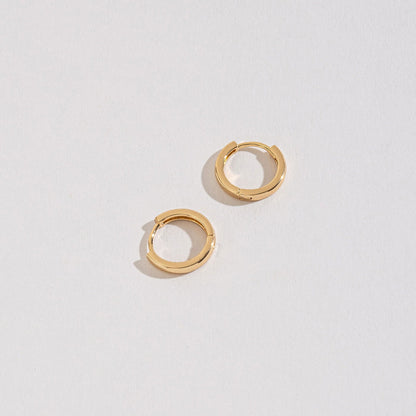 gold medium huggie hoops on a white background.