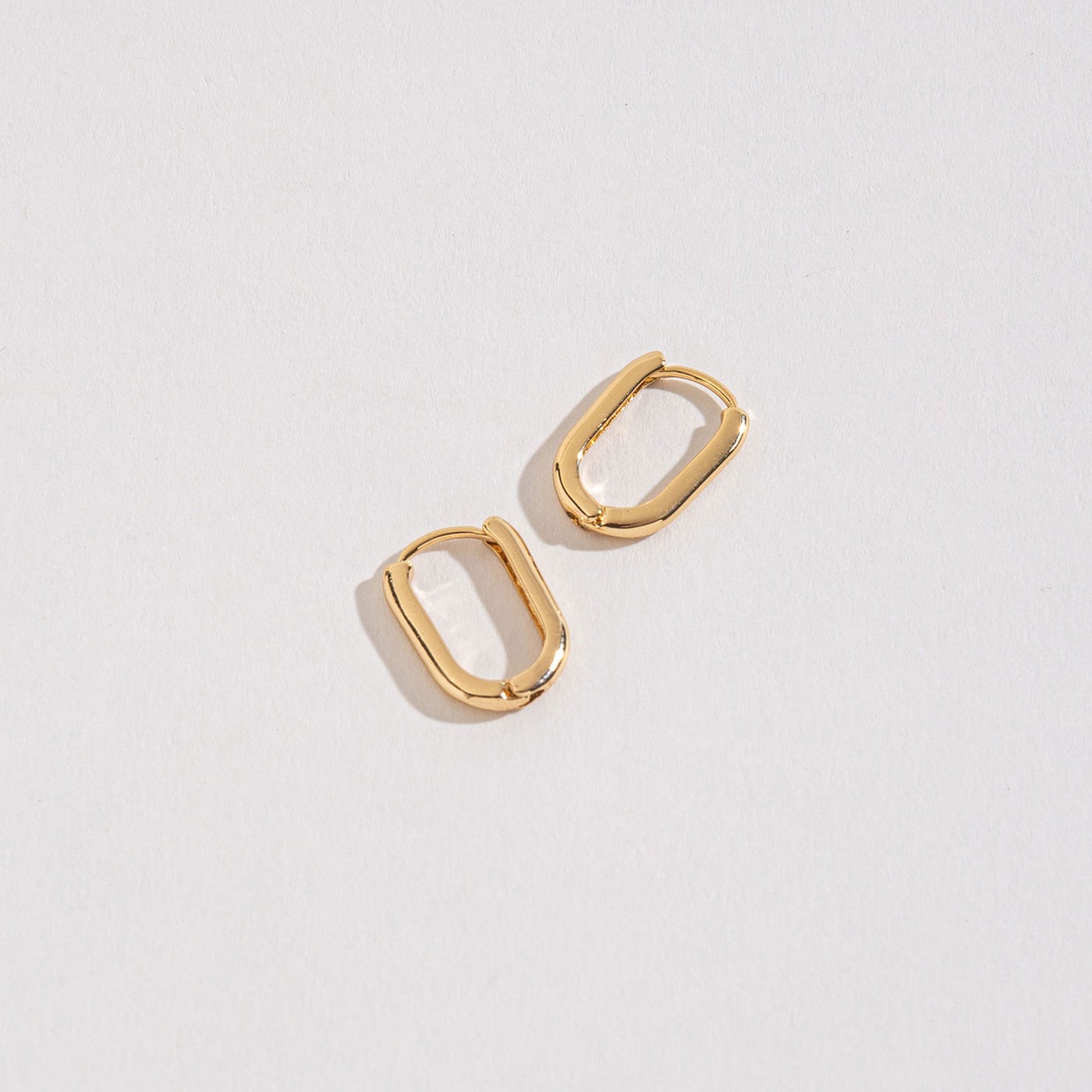 gold link huggie hoops on a white background.