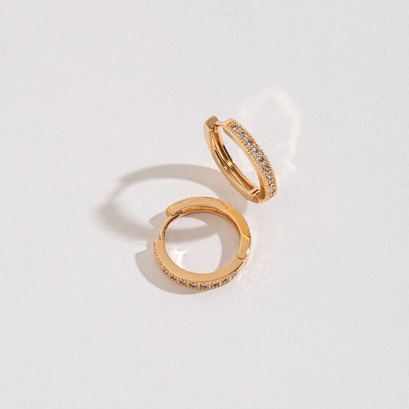 gold medium pave huggie hoops on a white background.